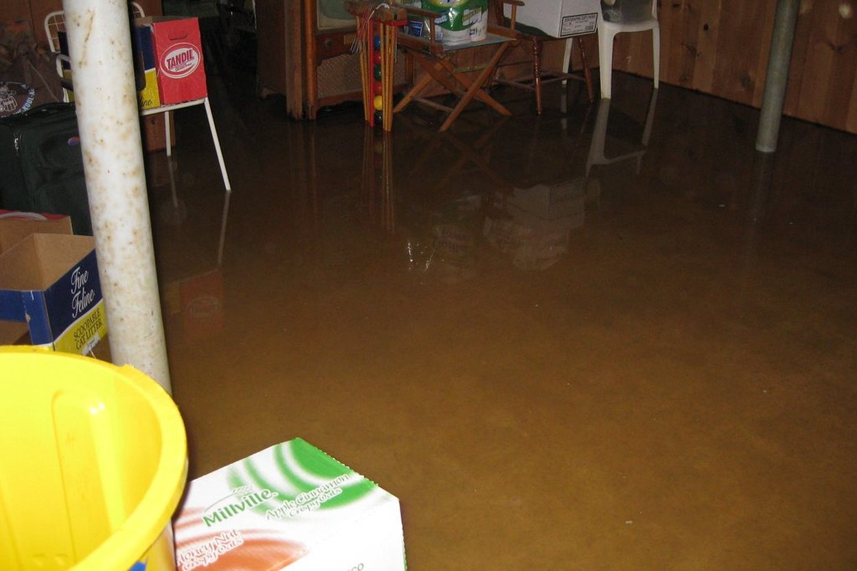 Flooded basement with water covering floor and partially submerging furniture and boxes.
