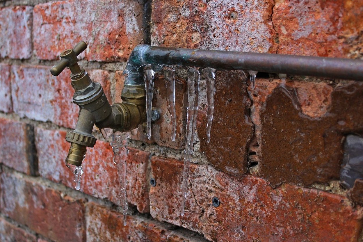 Icicles hanging from a frozen pipe in winter
