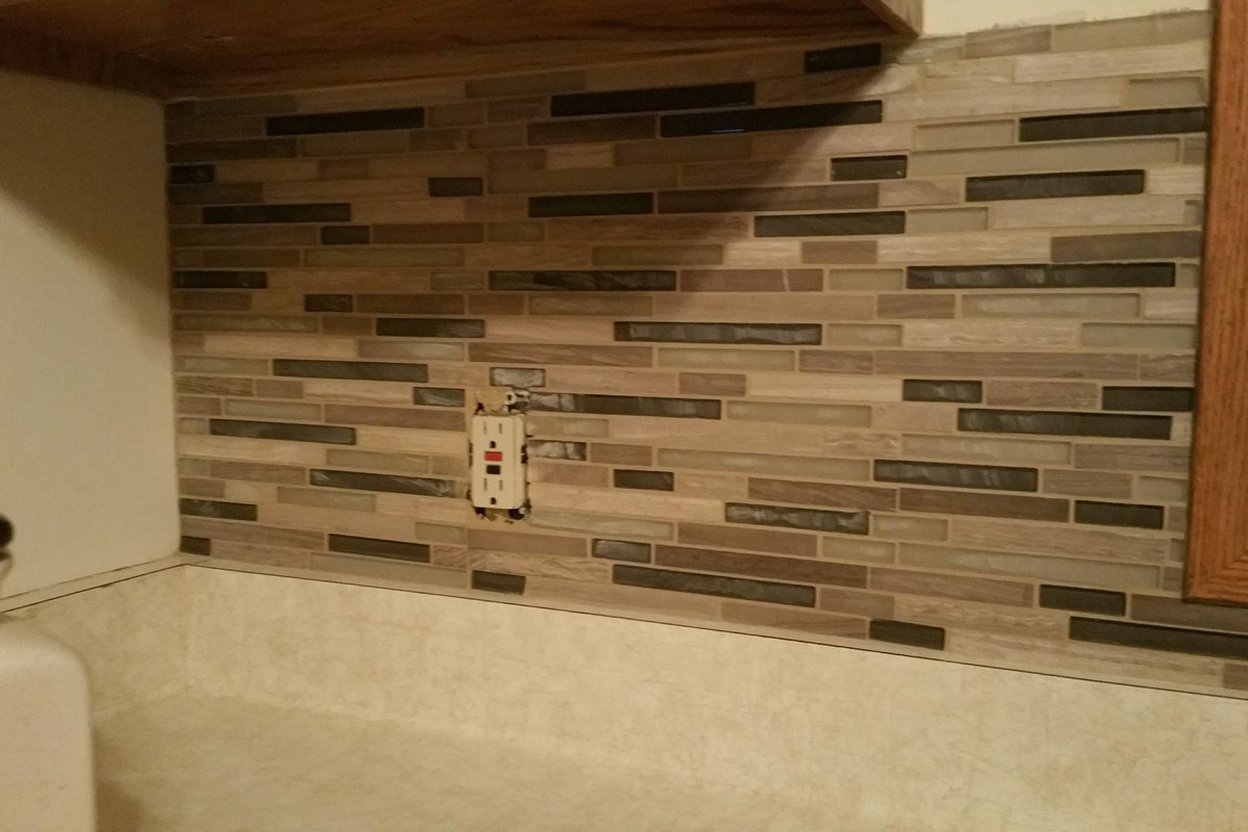 An outlet on a tile backsplash beside a kitchen countertop