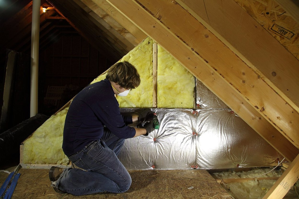 A person installing insulation in an attic