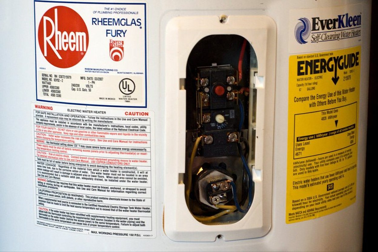 Rheem Fury electric water heater with access panel open showing internal components.