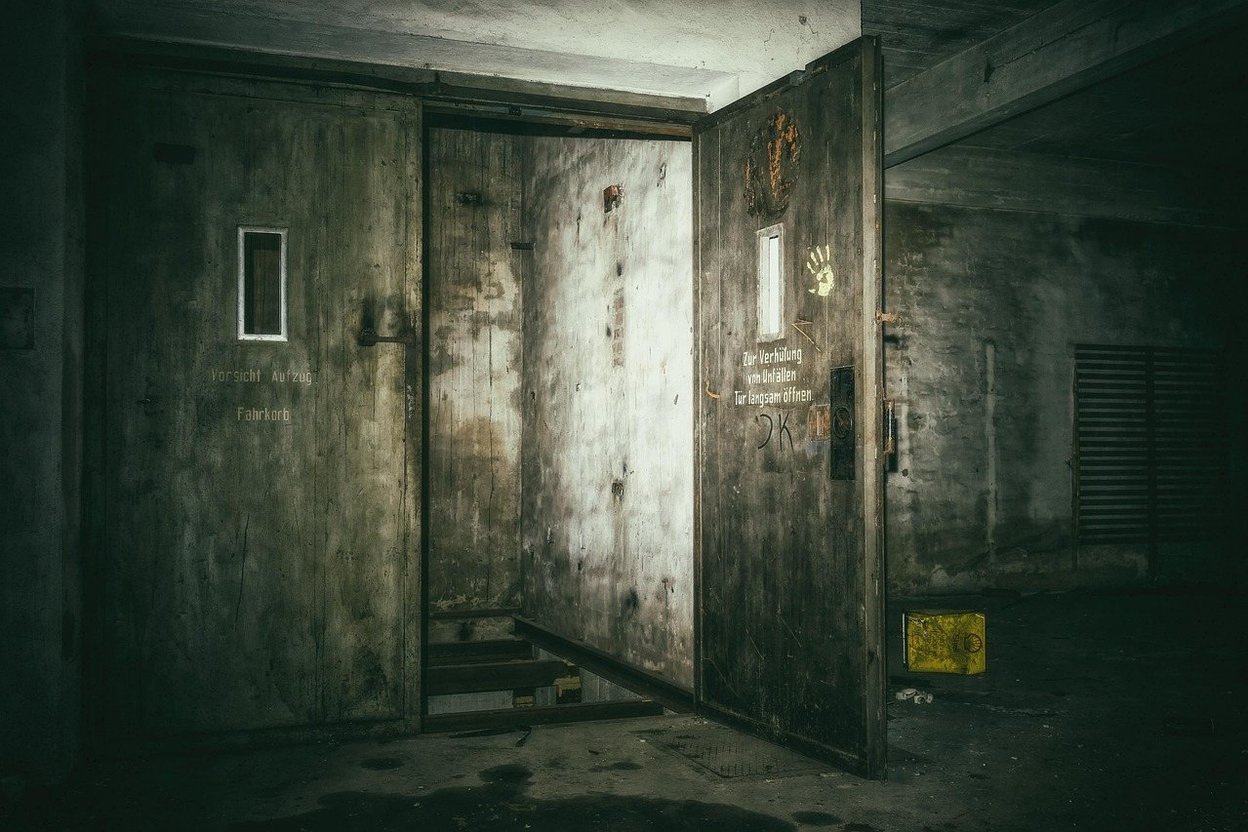 A heavy, weathered basement door with warning signs.