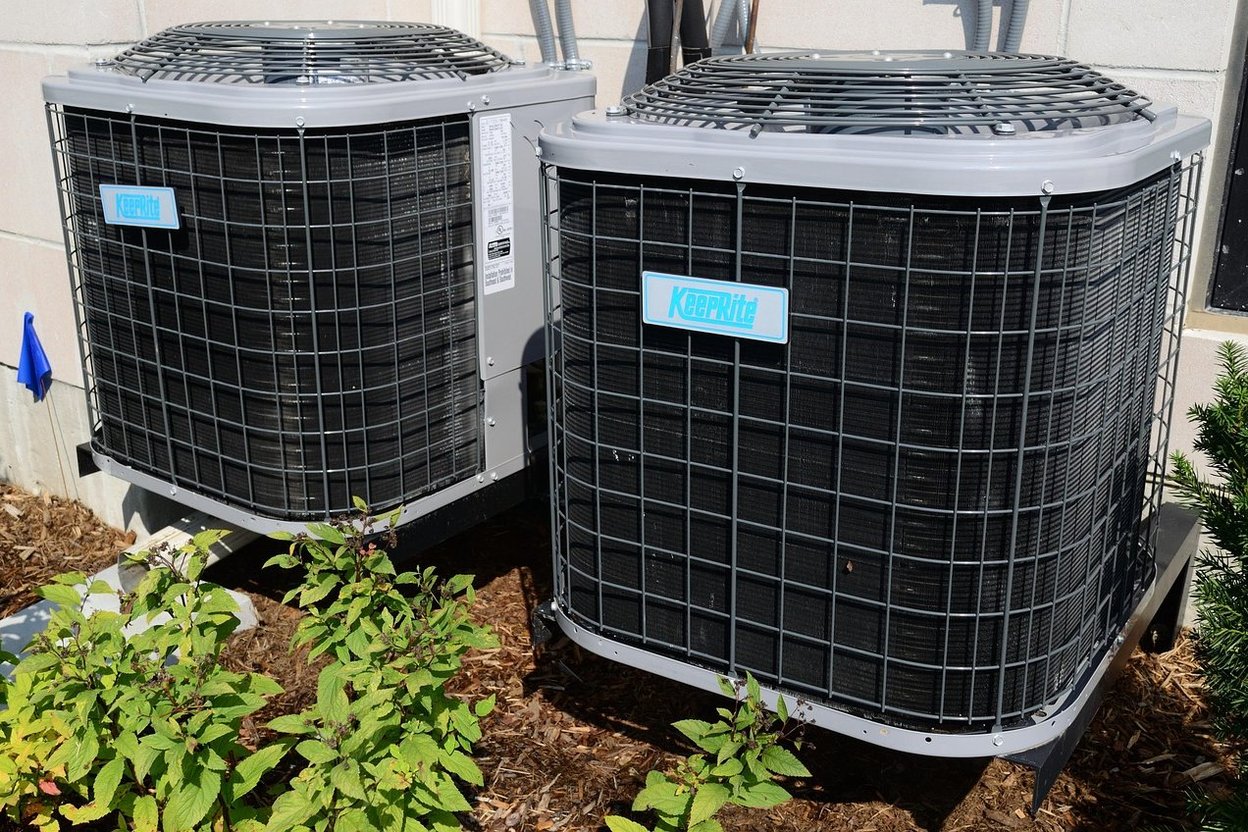 Two outdoor air conditioning units with protective grilles and brand labels.