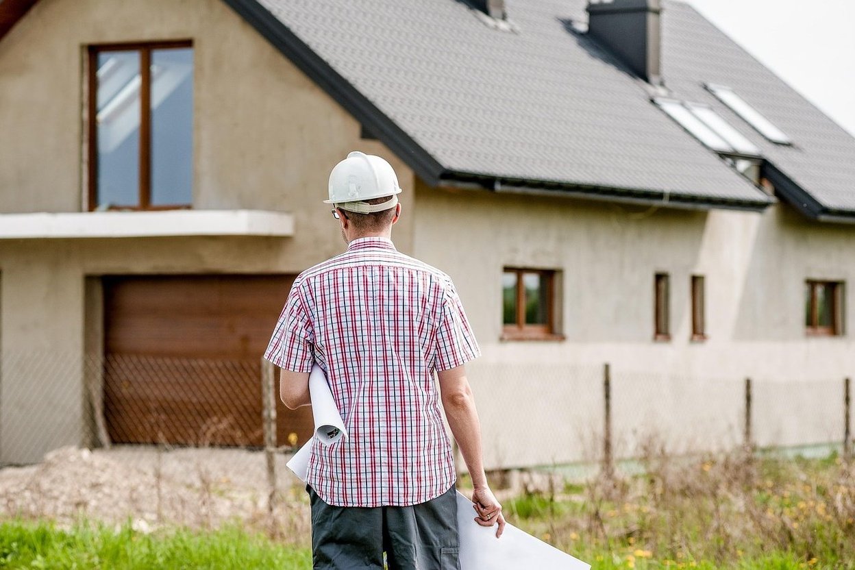 Architect reviewing blueprints of a modern house under construction.