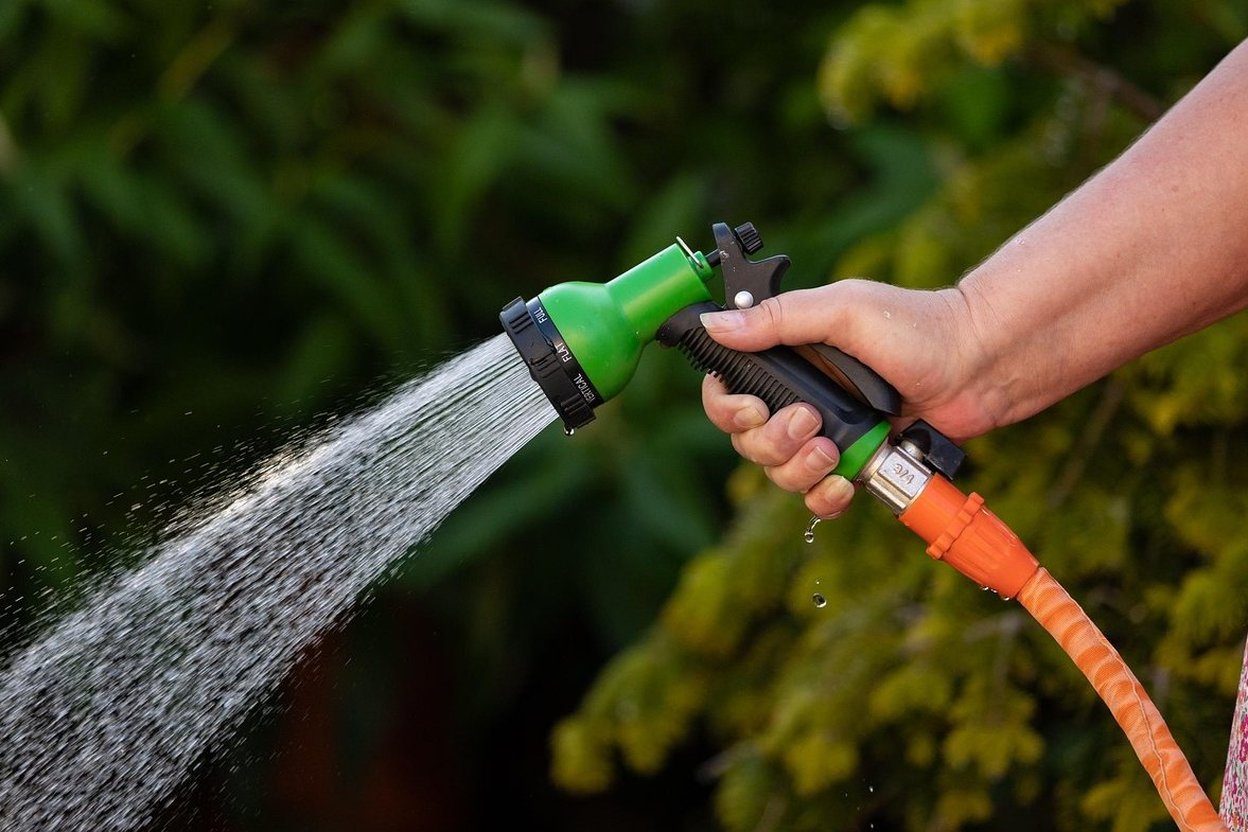 An outdoor hose bib on a house exterior wall with the garden hose disconnected and a foam faucet cover fitted over the spigot.