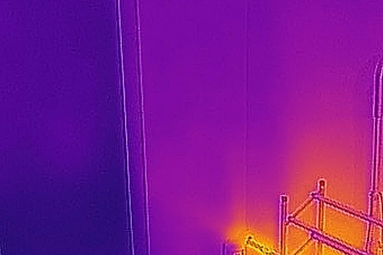 Thermal camera image showing a warm metal rack against a cooler wall.