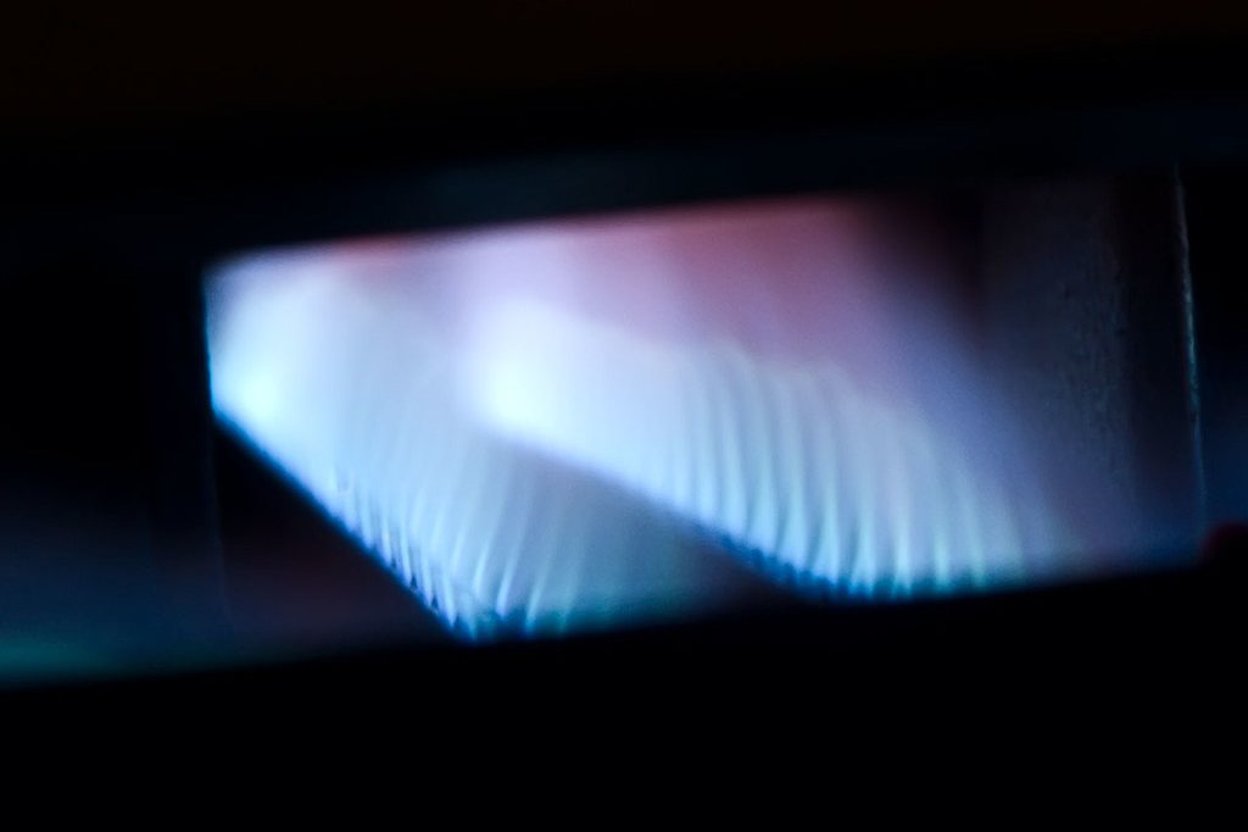 Blue flame of a gas stove burner in low light.