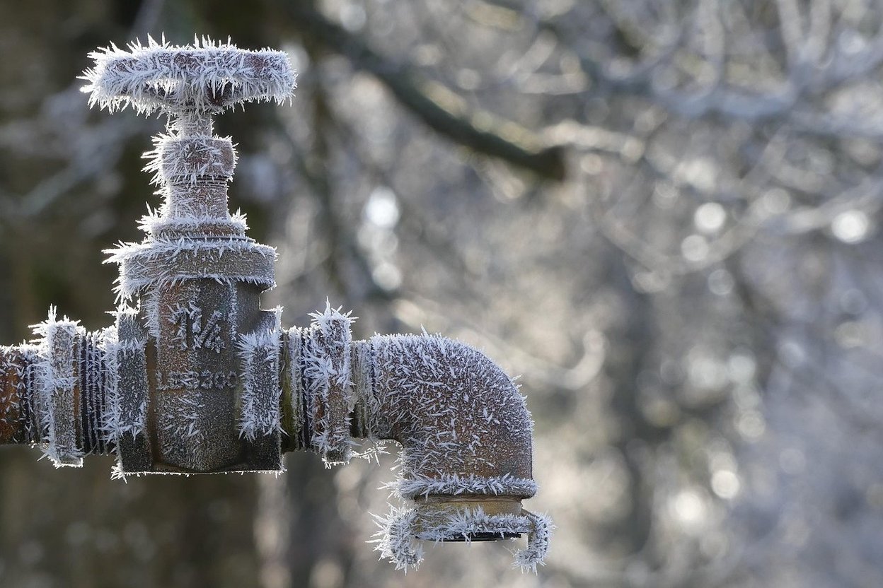 An old outdoor water tap covered in frost and ice crystals