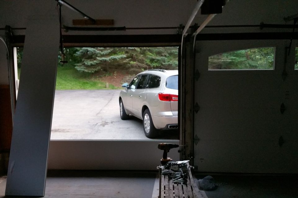 Looking out from inside a garage through an open door, with the door tracks along the ceiling