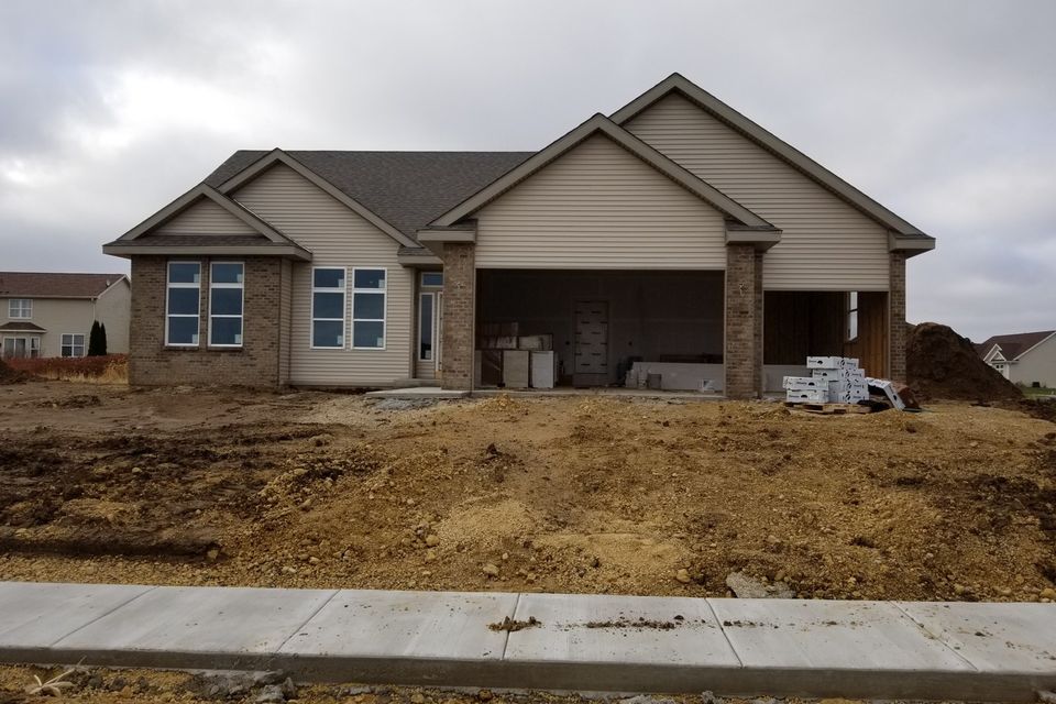 A new house with freshly graded bare dirt sloping down to the sidewalk