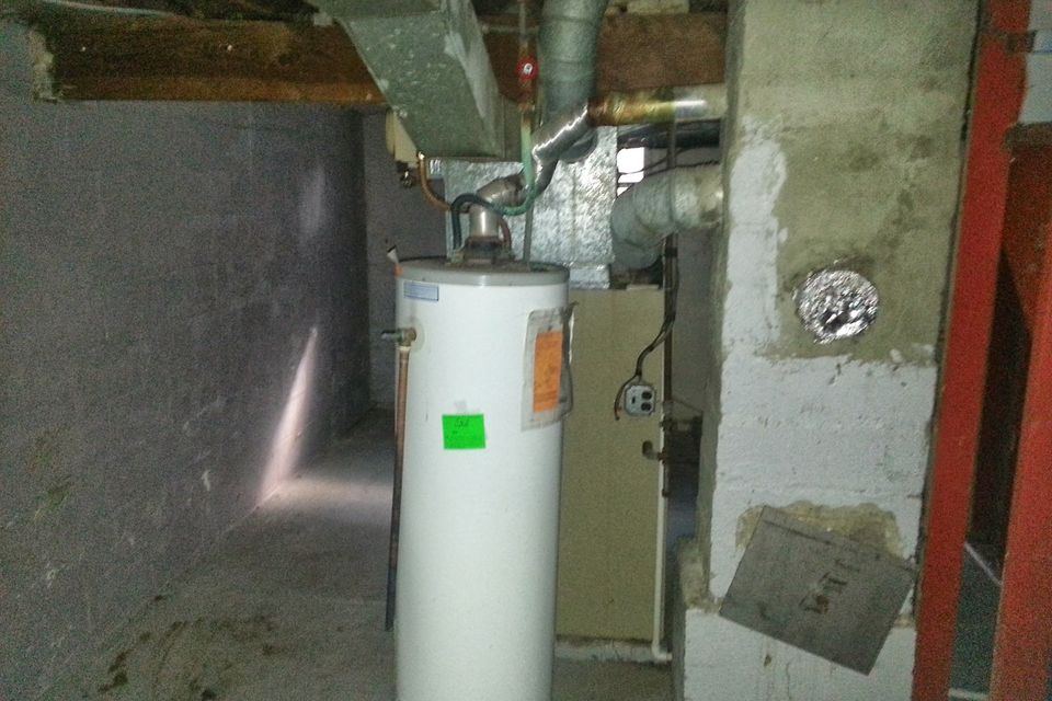 An older electric water heater in an unfinished basement