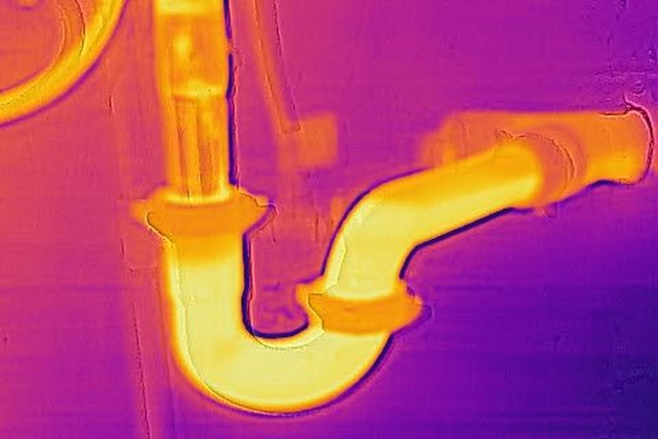 Thermal image of the pipes under a sink, with the hot water line glowing.